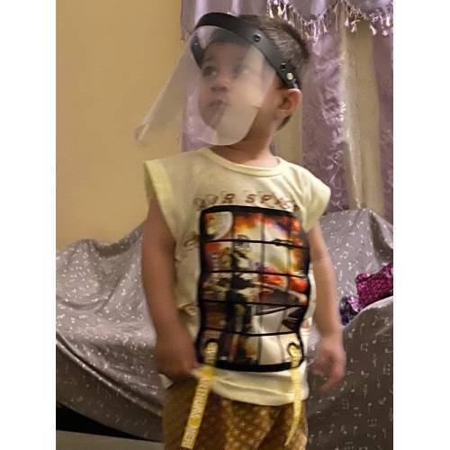 Kids Protective Face Sheild Professional Grade Face Mask - Shield Professional Grade Face Mask worn by a young child, featuring a clear plastic visor with a black adjustable headband.