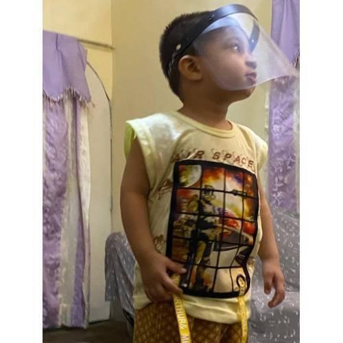 Kids Protective Face Sheild Professional Grade Face Mask - Shield Professional Grade Face Mask worn by a young child, featuring a clear plastic visor attached to a black adjustable headband.