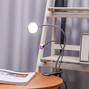 Koocu 7005 Lamp 2 In 1 With UV Light And LED Flash Light - a silver dual-neck desk lamp clipped to a wooden table with one white and one purple light.