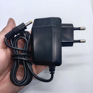 LG U+ 5V 2amp Power Adaptor Kecil Jack - a black wall-plug power supply with a long cable and a yellow-tipped barrel connector held in a hand.