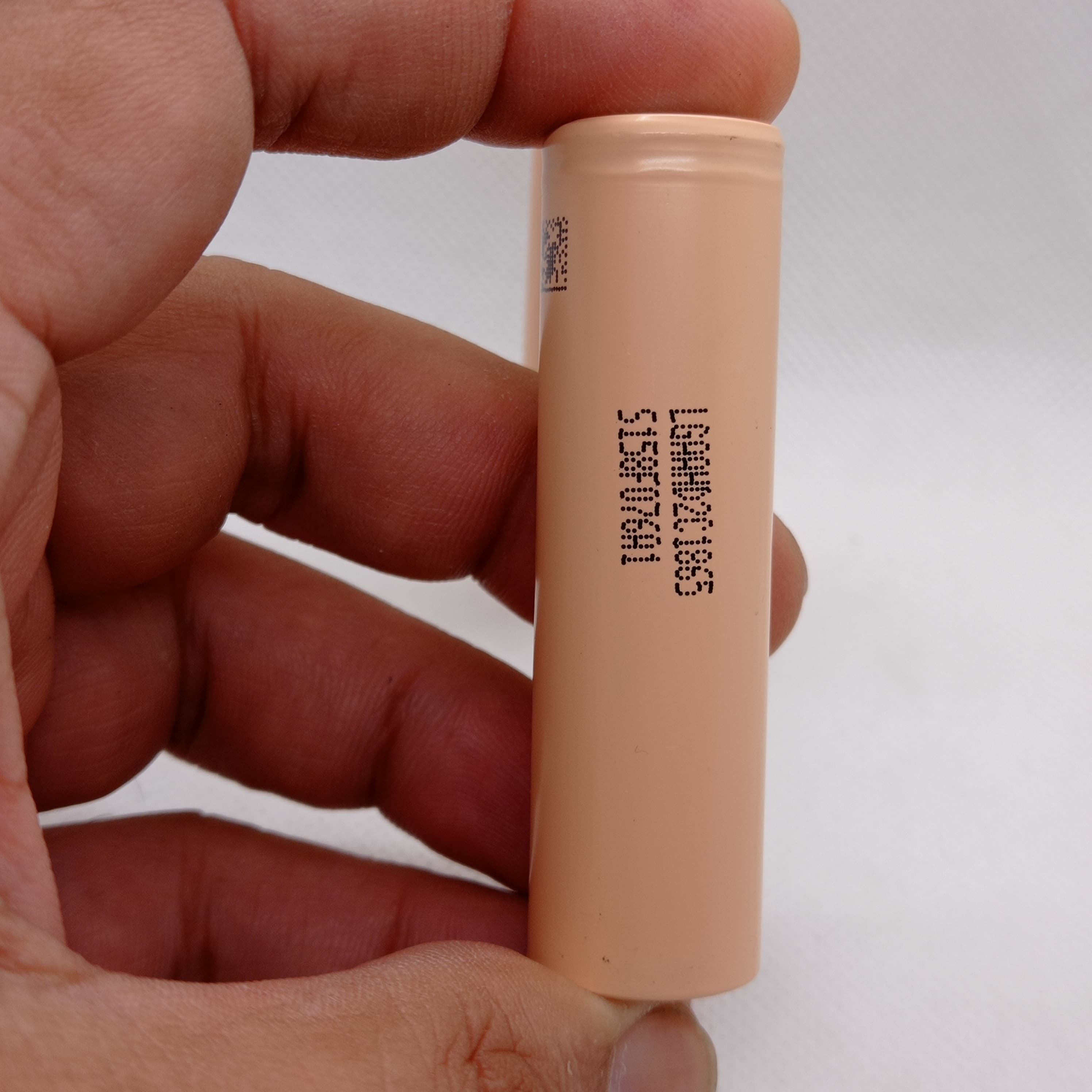 LGAAHD2C1865 3.7V 2100mAh High-drain 18650 Li-ion Battery - a peach-colored cylindrical cell held in a hand, showing the printed model number and code on its side.