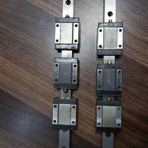 Linear Bearing Slide Rail CNC Router - two silver metal rails, each featuring three rectangular black and silver sliding blocks with brass grease nipples.