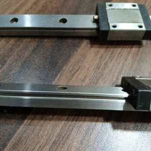 Linear Bearing Slide Rail CNC Router - two silver metal rails with black sliding blocks positioned on a dark wood-grain surface.