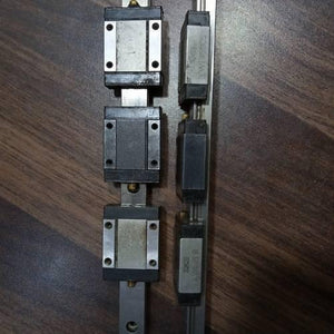 Linear Bearing Slide Rail CNC Router - two metal guide rails with multiple black sliding blocks attached, arranged vertically on a wooden surface.
