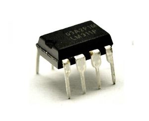 LM311 - a black 8-pin DIP integrated circuit chip with metal legs, shown from a slightly elevated angle against a white background.