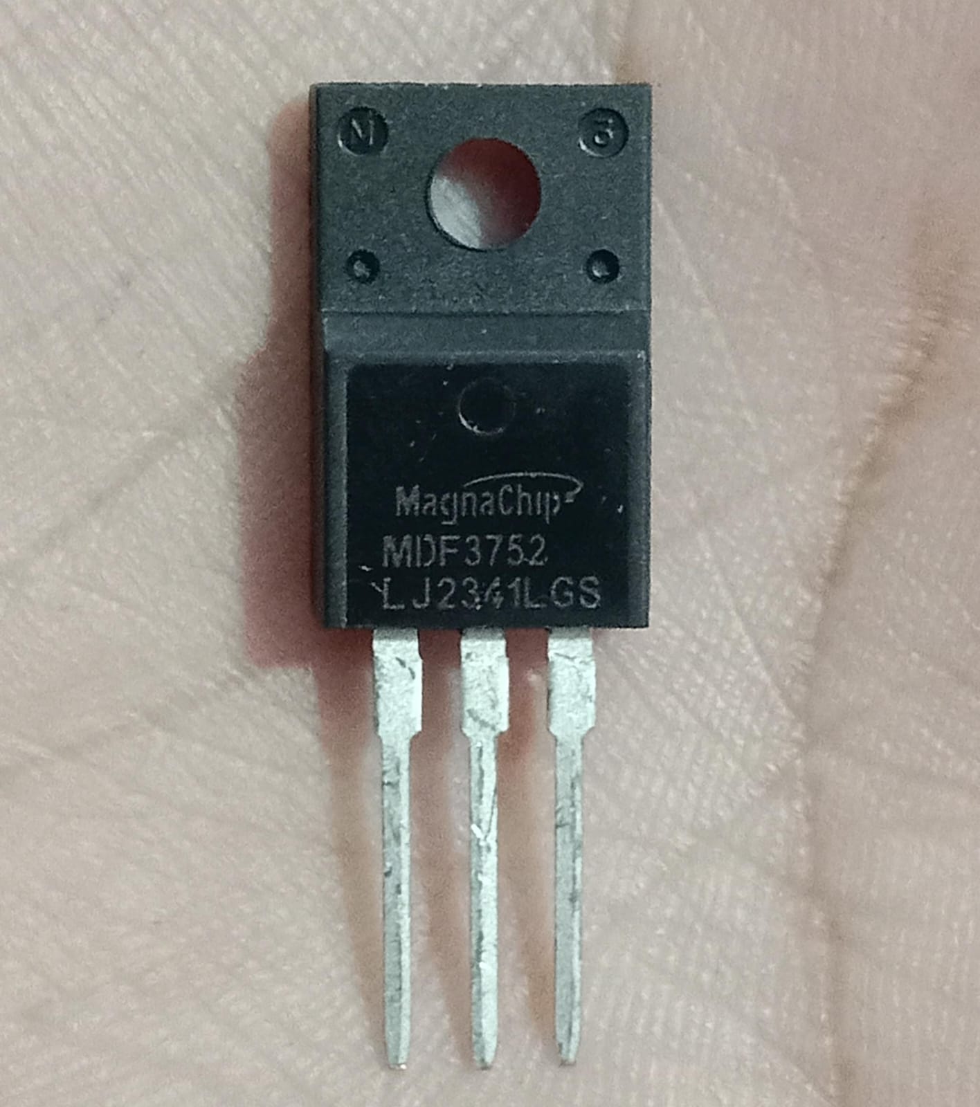 MagnaChip MDF3752 N-Channel Power MOSFET - a black, three-pin electronic component held against a hand, showing the printed model number and logo.