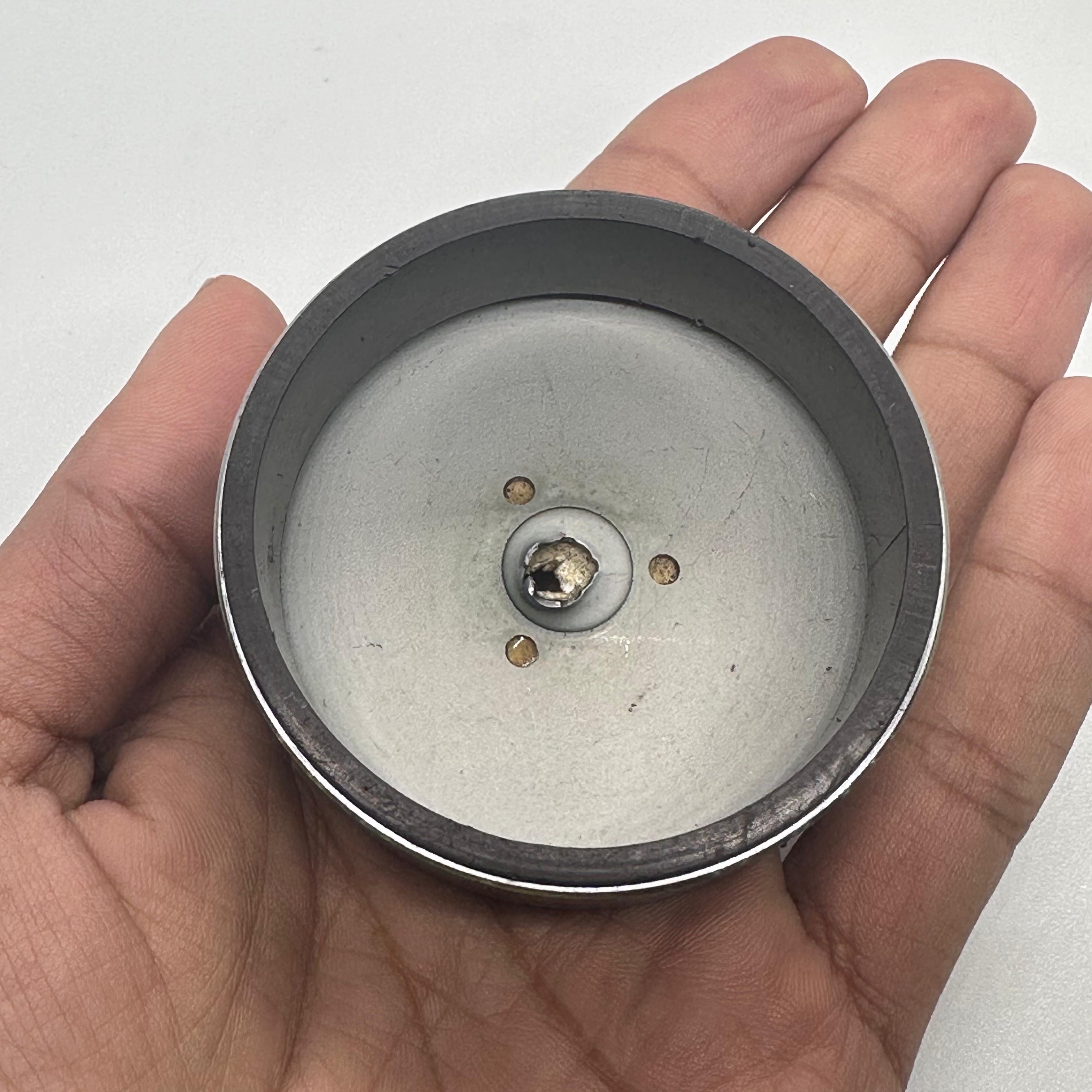 Magnet for storing screws and metal - shown as a close-up of a circular grey metallic tray with a central magnet held in a human hand.