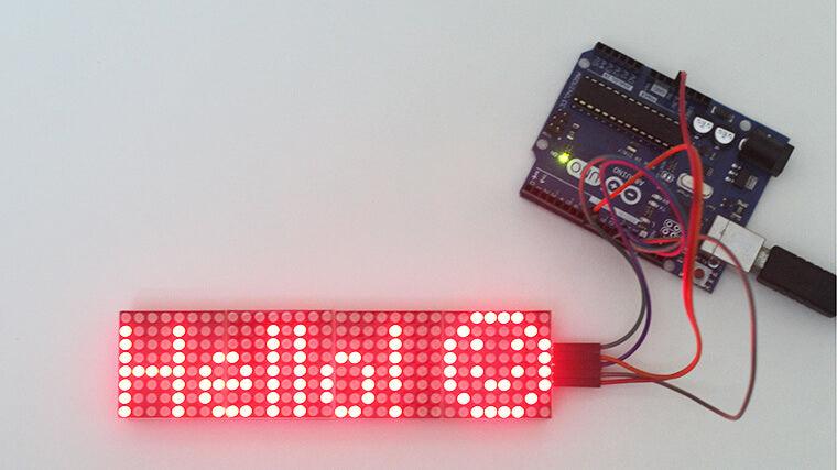 MAX7219 32×8 Dot Matrix Display Module - connected to an Arduino board, showing the red illuminated text "Hello :)" on its LED matrix display.