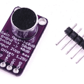 MAX9814 Microphone Amplifier Module - a purple circuit board with a microphone and five pin headers, shown next to a separate five-pin connector strip.
