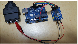 MCP2515 Can-bus Controller And Transceiver Module - connected to an Arduino Uno board and a black OBDII diagnostic connector via jumper wires and a two-pin screw terminal.