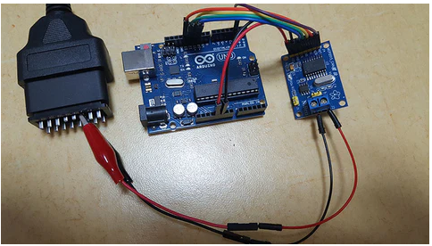 MCP2515 Can-bus Controller And Transceiver Module - connected to an Arduino Uno board and a black OBDII diagnostic connector via jumper wires and a two-pin screw terminal.