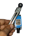 Me-8108 Mini Limit Switch - held in a hand, featuring a blue rectangular body with a metal roller lever arm and a label showing terminal numbers 1, 2, 3, 4.
