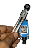 Me-8108 Mini Limit Switch - held in a hand, featuring a blue rectangular body with a metal roller lever arm and a label showing terminal numbers 1, 2, 3, 4.