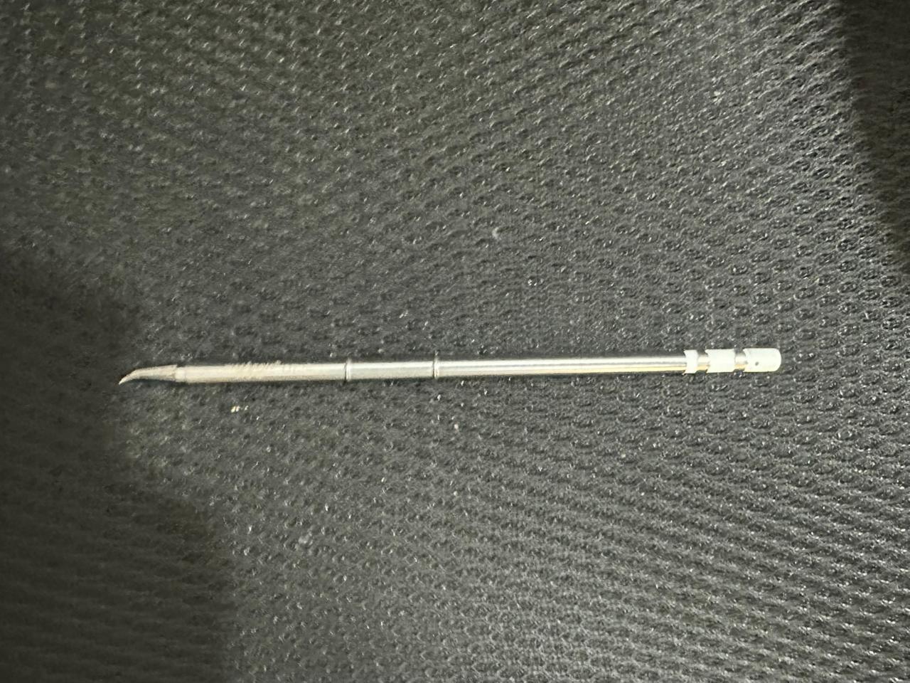 Mechanic T12 Soldering Iron Tip - Professional Grade Replacement Tip - a silver-coloured, slender metal replacement tip with a curved point, shown as a close-up against a textured black background.