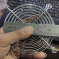 Metal Exhaust Fan Guard Grill – 4 Inch | Protective Jali Cover for Cooling & Ventilation - shown being measured with a metal ruler, displaying its circular silver wire frame and mounting holes.