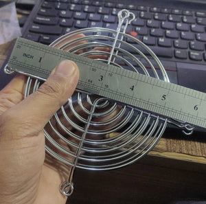 Metal Exhaust Fan Guard Grill – 4 Inch | Protective Jali Cover for Cooling & Ventilation - shown being measured with a metal ruler, displaying a circular silver wire mesh design held by a hand.