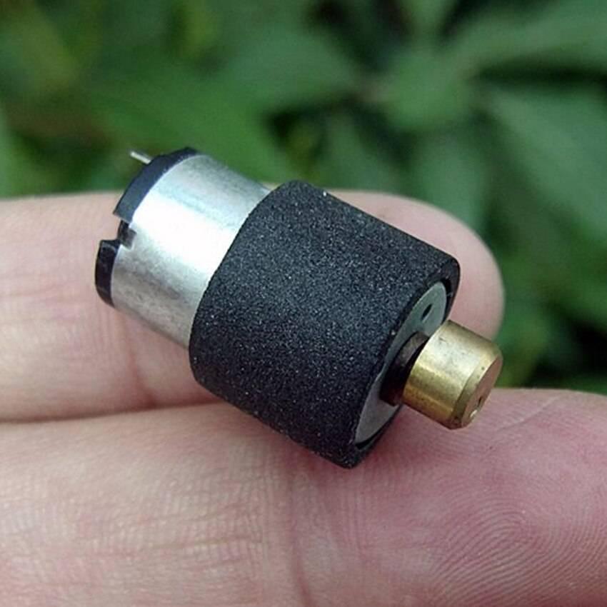 Micro Vibration Motor Vibrator Dc3v-6V 1220 - shown as a small cylindrical silver motor with a black foam sleeve and a brass-colored tip held in a hand.
