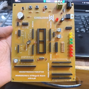 MikroDuino-II AVR ATMEGA32 Arduino Compatible Board Without LCD ,IC And Arduion - a yellow circuit board with a 40-pin IC socket, multiple pin headers, LED indicators, and buttons, held in a hand.