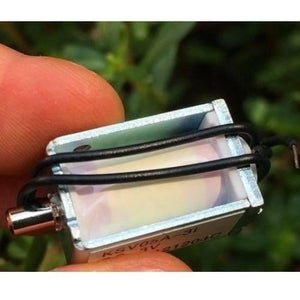 Mini 3V DC Solenoid Valve KSV05A Normally Open For Gas Air Valve - a rectangular metallic valve with a protruding nozzle and two black wires, held between fingers against a blurred background.