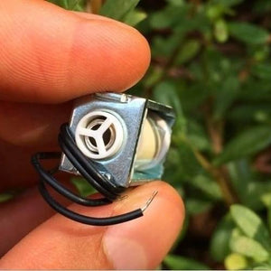Mini 3V DC Solenoid Valve KSV05A Normally Open For Gas Air Valve - a close-up view held by fingers showing the silver metal body, white plastic port, and two black wire leads.