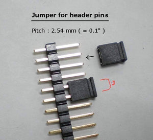 Mini Jumpers Hard Drive Jumper - shown as a close-up of two black plastic jumpers positioned on a strip of metal header pins with a 2.54 mm pitch.