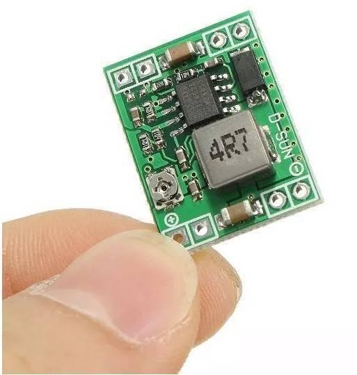 Mini MP1584EN DC-DC Buck Adjustable Step Down Module 4.5V-28V Input 0.8V-20V Output - shown held by fingers, featuring a green rectangular circuit board with a potentiometer and inductor.