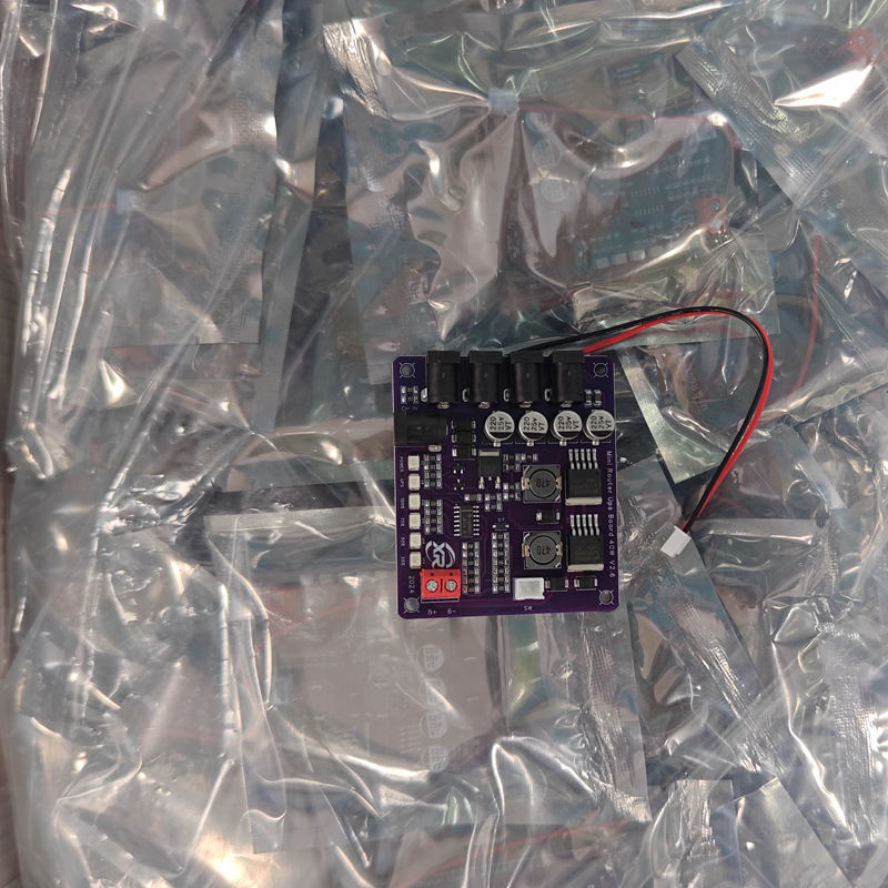 Mini Router UPS Board 40W V2.6 for Router & Modem in Pakistan - a purple circuit board with four DC ports, a red terminal block, and a two-wire connector, resting on plastic.
