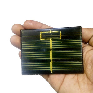 Mini Solar 60x80mm 0.50V - a rectangular black solar panel with gold-colored conductive grid lines held in a person's palm.