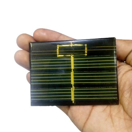 Mini Solar 60x80mm 0.50V - a rectangular black solar panel with gold-colored conductive grid lines held in a person's palm.