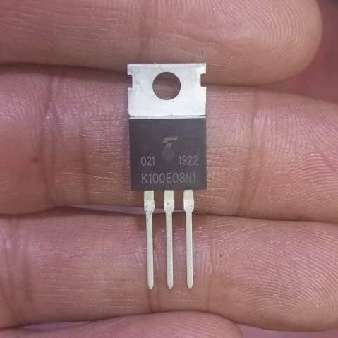MOSFET transistor K100E08N1 - a black three-pin electronic component with a metal heat sink tab, held between fingers.