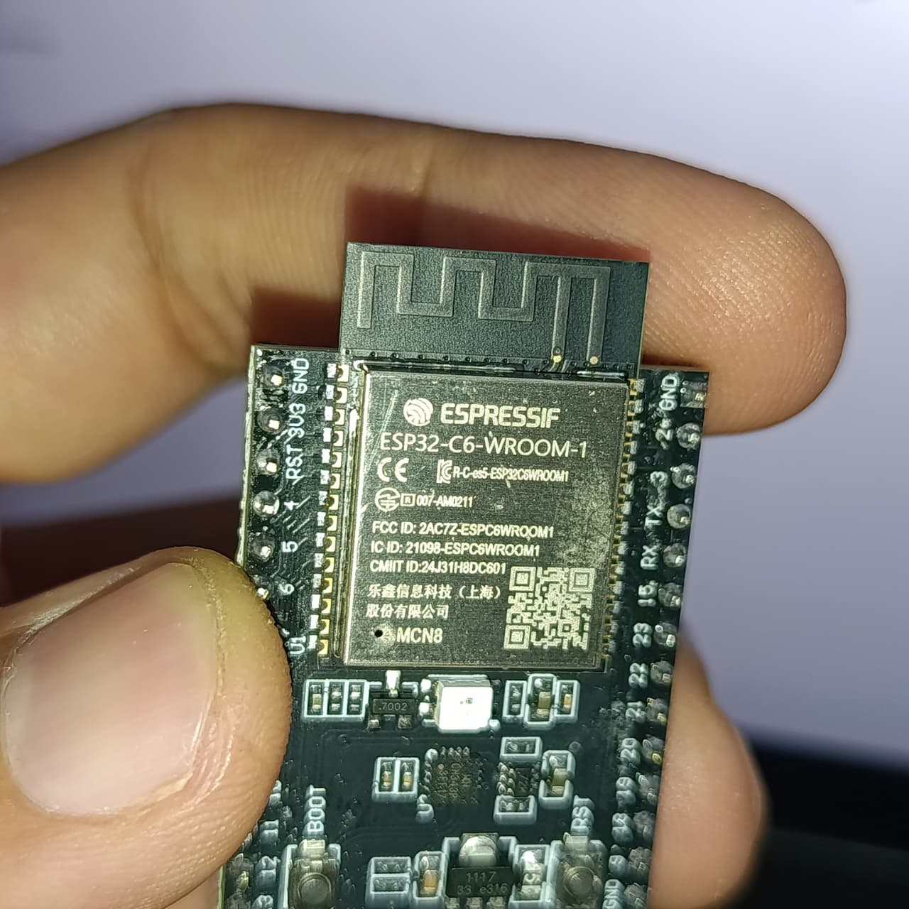 NANOESP32-C6 Development Board | ESP32-C6-WROOM-1-N4 | WiFi 6 + Zigbee + Thread | RISC-V 160MHz | 4MB Flash | Dual USB-C | RGB LED - a close-up showing the ESP32-C6-WROOM-1 module, integrated antenna, and labeled pin headers held by a hand.