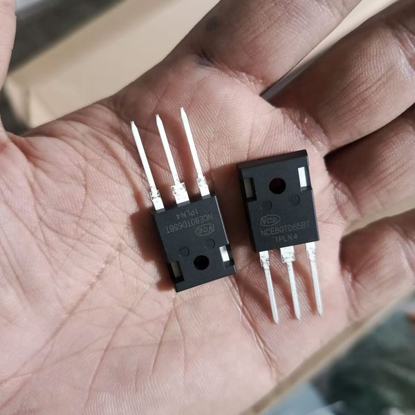 NCE 80TD65 IGBT MOSFET Power Semiconductor - two black three-pin power semiconductor components held in a hand.