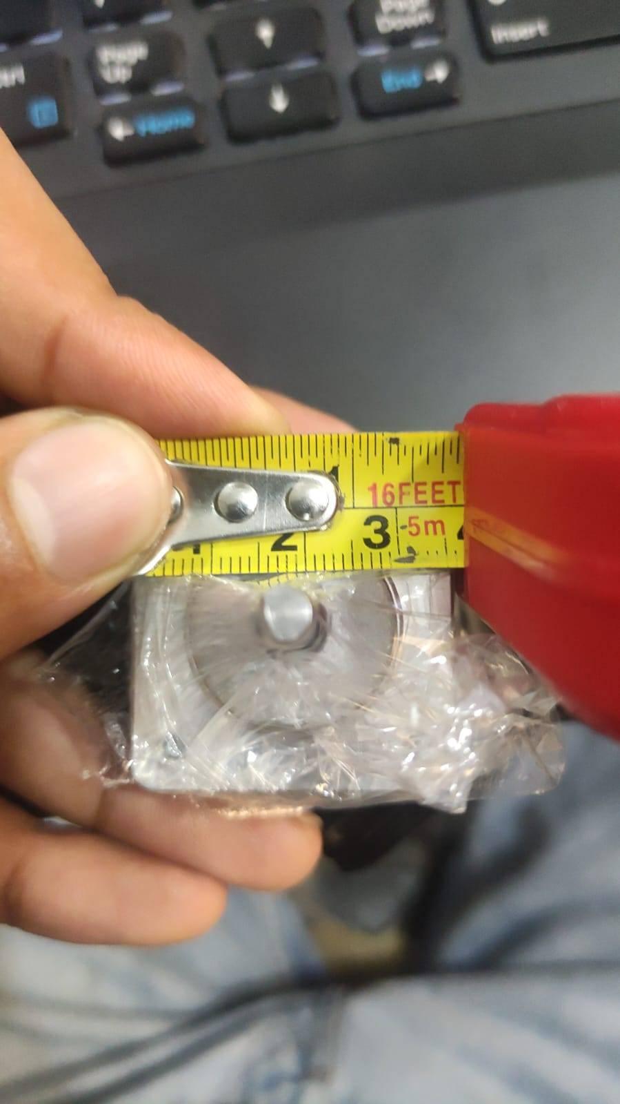 NEMA 11 stepper motor without connector - a close-up view showing the silver square-shaped motor body wrapped in plastic, being measured by a yellow tape measure.