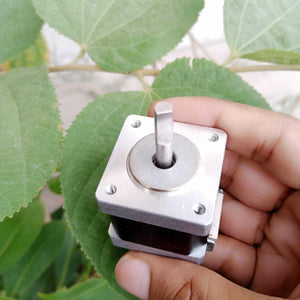 NEMA 11 stepper motor without connector - a close-up of the silver square mounting face and the central metal shaft held in a hand.