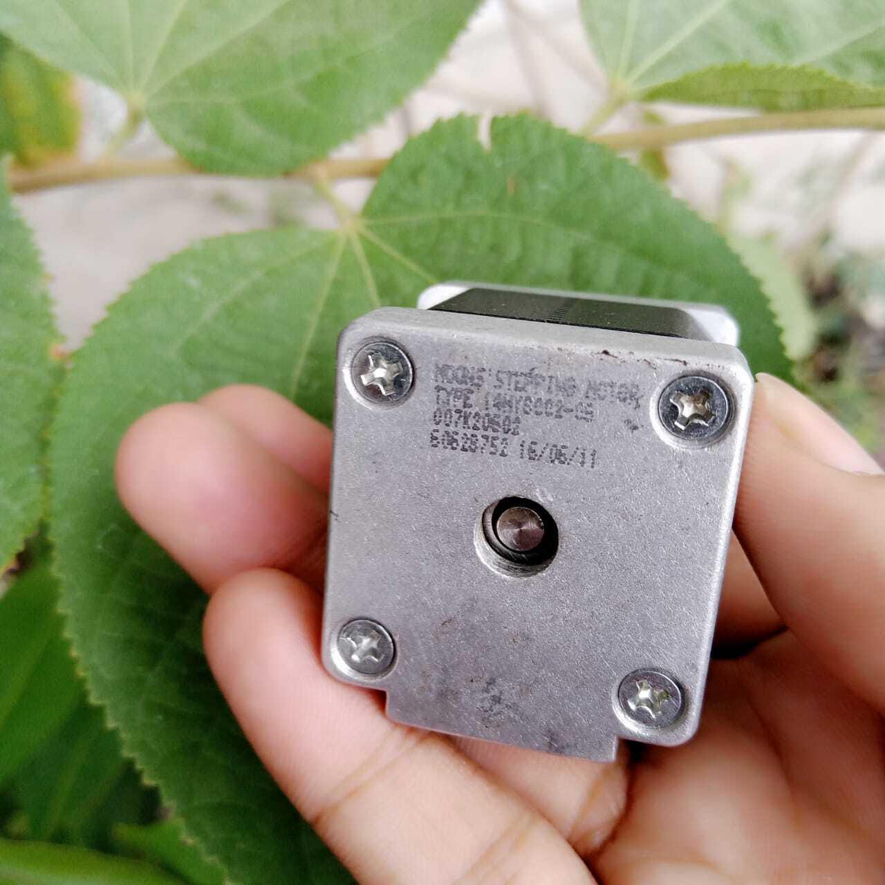 NEMA 11 stepper motor without connector - a close-up of the silver square front face with four mounting screws, a central shaft, and printed text including the date 16/06/11.