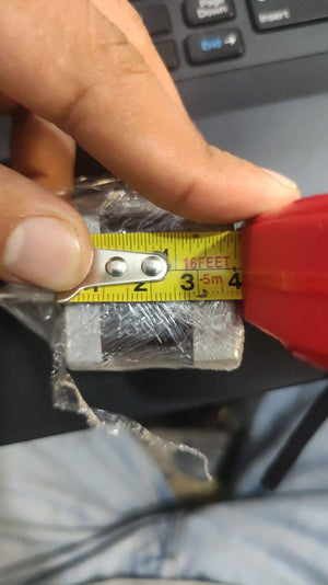 NEMA 11 stepper motor without connector - a close-up shot showing the silver-coloured motor body wrapped in plastic being measured with a yellow tape measure.