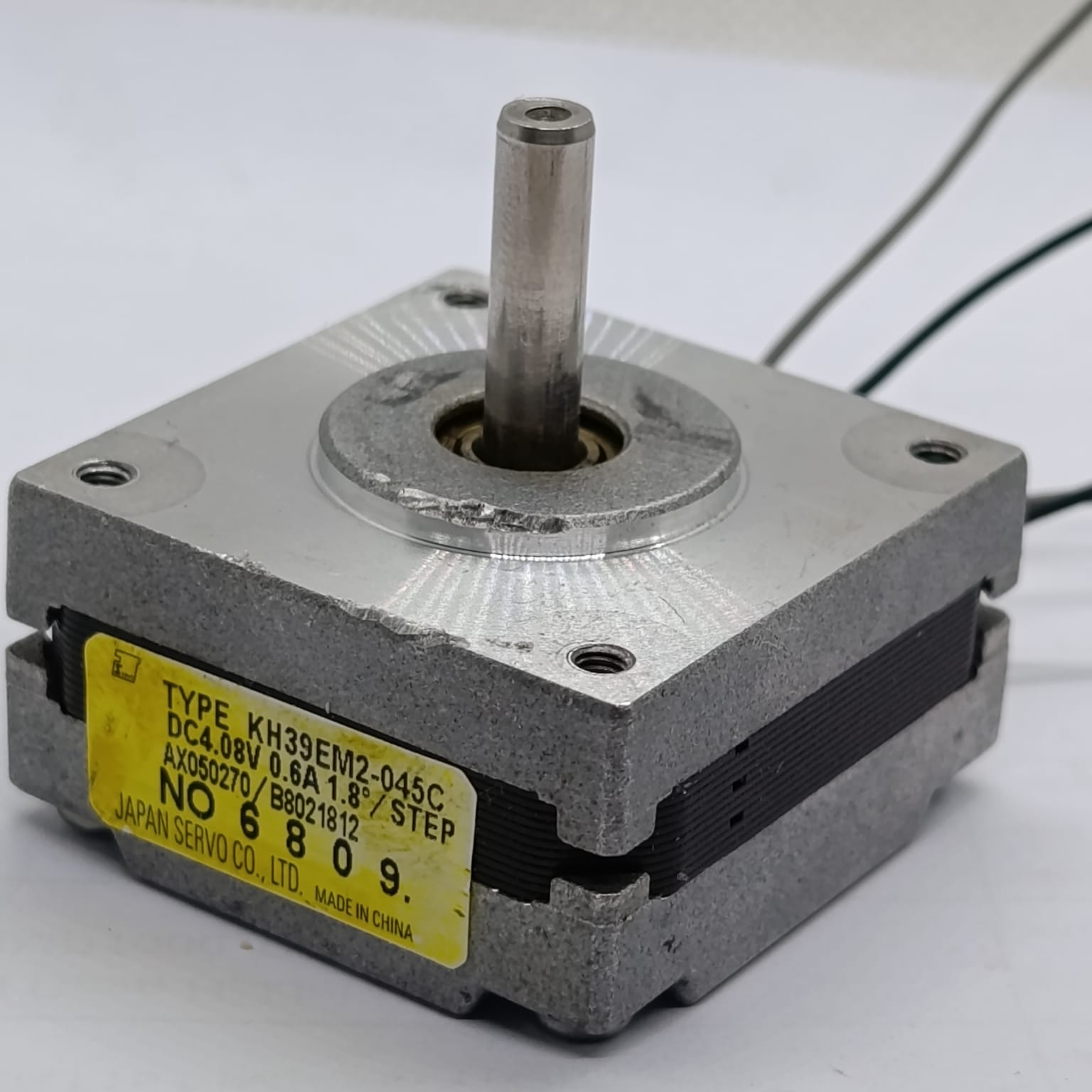 NEMA 14 Stepper motor KH39EM2-045C 0.6A JAPAN SERVO Pancake Stepper Motor - a silver and black square pancake motor with a central metal shaft and a yellow specification label on its side.