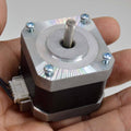 NEMA 17 4 Wire Stepper Motor NEMA17 Stepper Motor REFIRBISHED - shown as a silver and black square motor held in a hand with a central shaft and a white connector port.