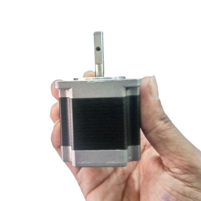 NEMA 20 Stepping Motor – Precision Control for Robotics, CNC & Automation | Digilog.pk - held in a hand, showing the silver metal casing, black motor body, and a single vertical shaft with a small hole.