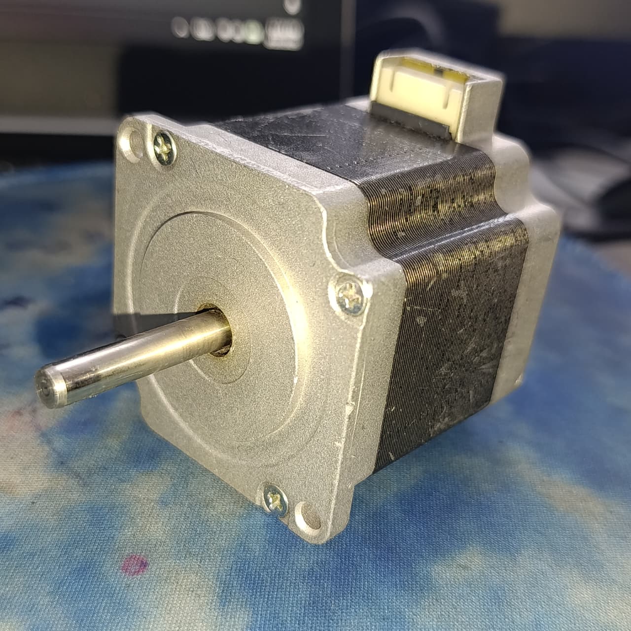 NEMA 23 Stepper Motor In Pakistan (1.5A–2.0A, 1.8°) - a silver and black square-bodied motor with a protruding metal shaft and a white electrical connector on the top edge.