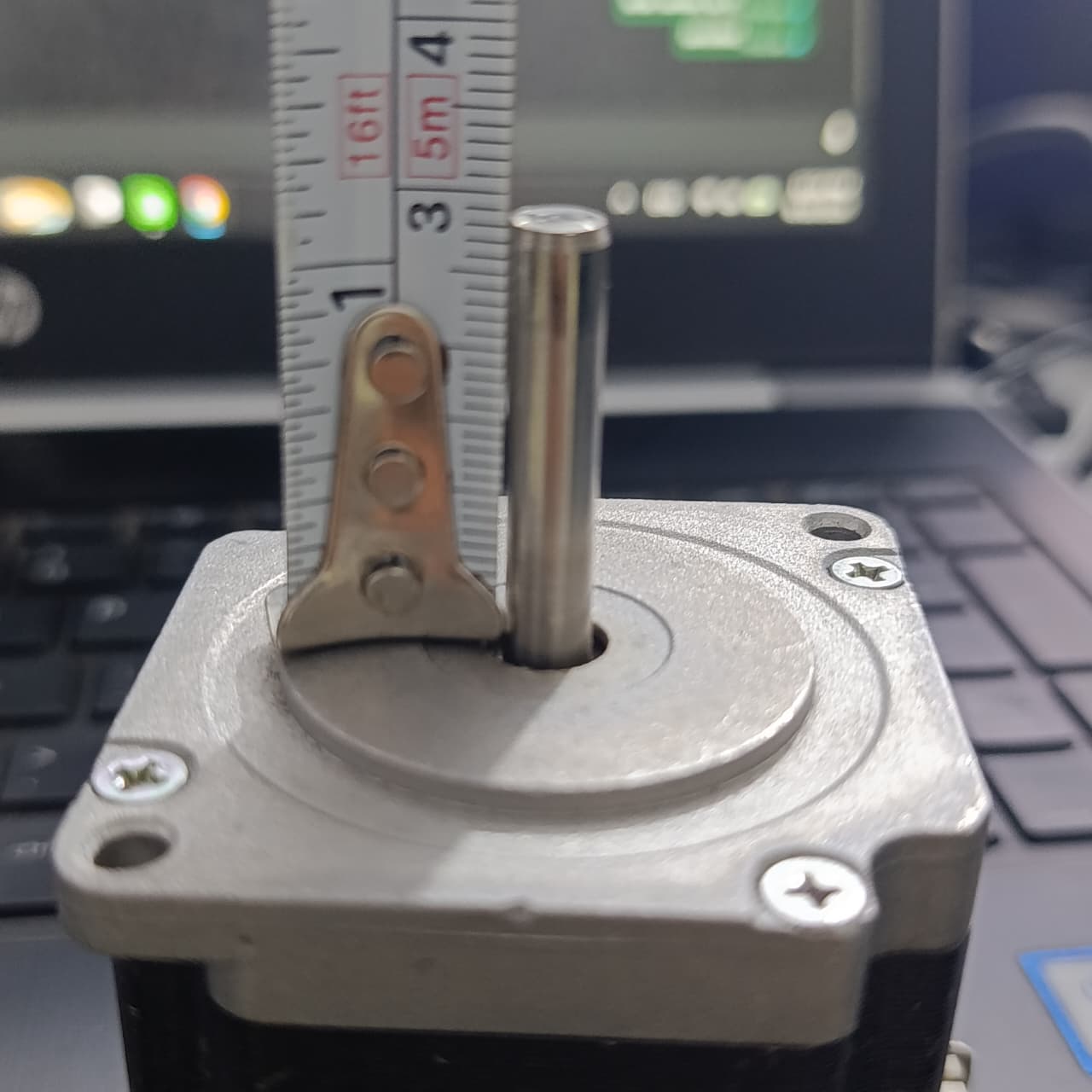 NEMA 23 Stepper Motor In Pakistan (1.5A–2.0A, 1.8°) - a close-up of the metal shaft being measured with a tape measure against the motor's top housing.