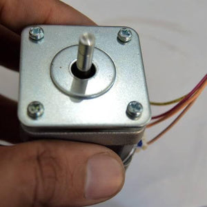 NEMA17 NEMA 17 Stepper Motor For 3D Printer And CNC - a close-up view of the square silver-toned front face with a central rotating shaft and four mounting screws, held by a hand.