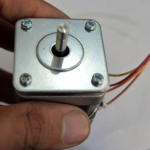 NEMA17 NEMA 17 Stepper Motor For 3D Printer And CNC - a close-up view of the square silver-toned front face with a central rotating shaft and four mounting screws, held by a hand.