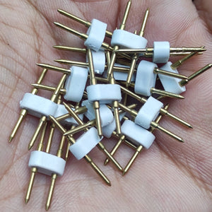 Neon Light Connector Pin - a close-up shot of several white plastic connectors with two sharp gold-coloured metal pins, held in a person's palm.