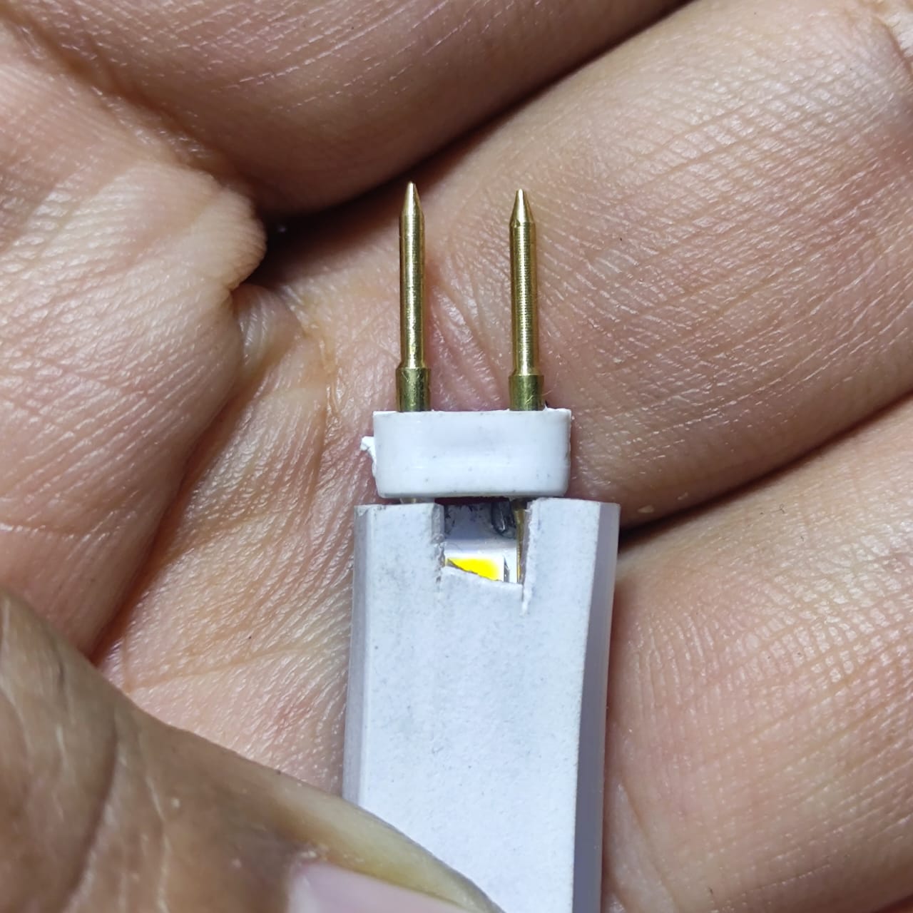Neon Light Connector Pin - a close-up view of a white plastic connector with two gold-colored metal pins inserted into a white neon light strip.