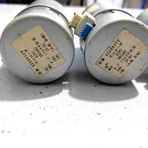 Nisca Servo DC Motor With Encoder NF5475E DC 24V To 38V And 3500 To 5000RPM - close-up of two cylindrical motor rear ends featuring white labels with Japanese text and technical specifications.