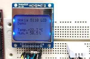 Nokia 5110 Monochrome Display Screen - text on a blue backlit screen with eight pins labeled RST, CE, DC, Din, Clk, Vcc, BL, and Gnd on a breadboard.