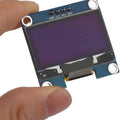 OLED 1.3 Inch Display Module 128x64 I2C Communicate 4pin SSD1106 Blue Text Color - held by a hand, showing its blue screen, four connection pins labeled GND, VCC, SCL, and SDA.