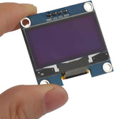 OLED 1.3 Inch Display Module 128x64 I2C Communicate 4pin SSD1106 Blue Text Color - held by a hand, showing its blue screen, four connection pins labeled GND, VCC, SCL, and SDA.