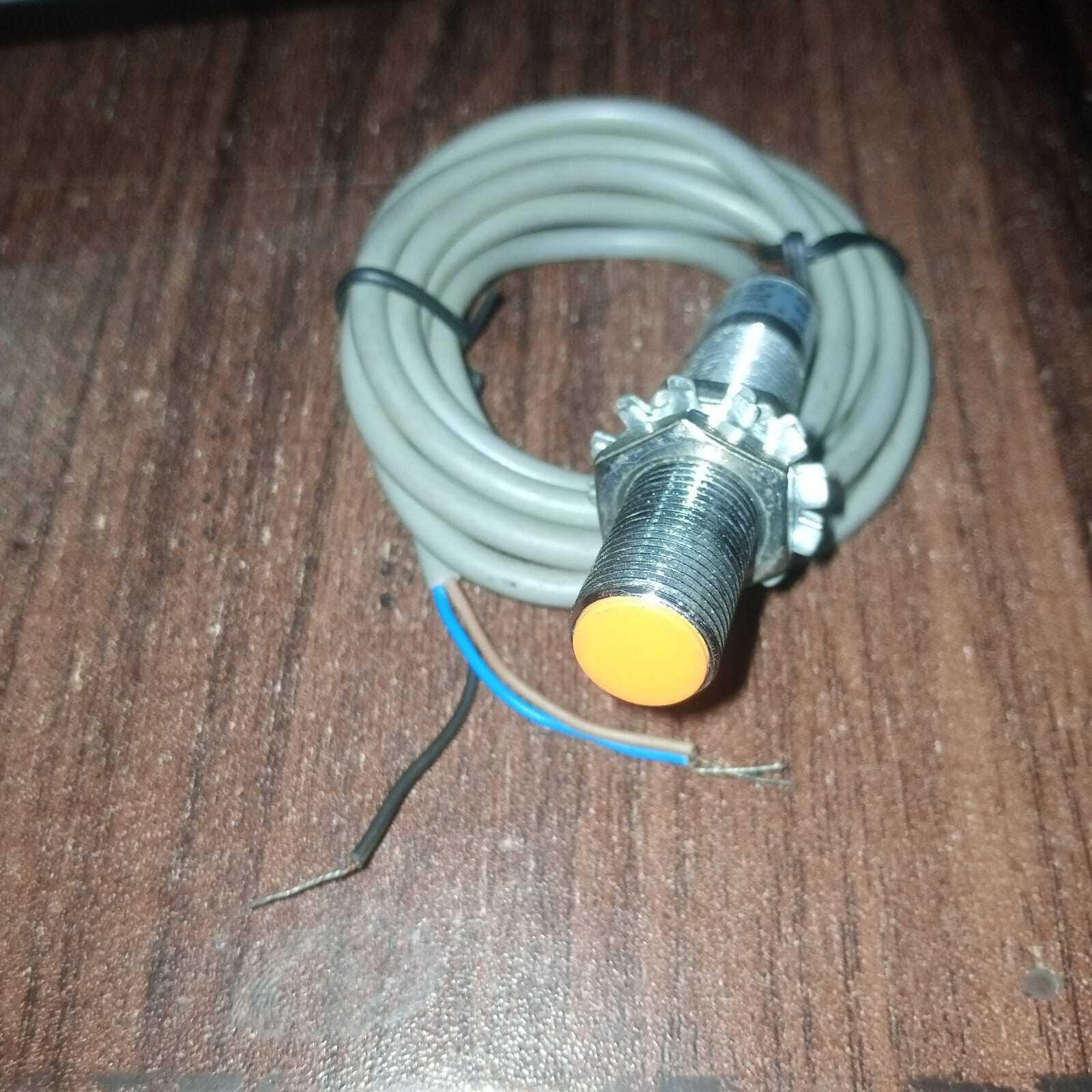 Omron Inductive Proximity Sensor Switch E2e-X2E1 - a cylindrical metal sensor with an orange tip, two mounting nuts, and a grey three-wire cable.